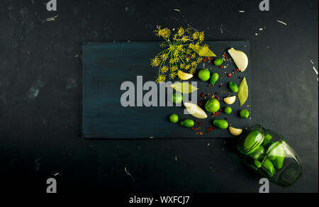 Tomates LÉGUMES ET ÉPICES AU CONSEIL. L'AIL ANETH TOMATES OIGNONS ÉPICES SUR UNE PLANCHE EN BOIS FONCÉ SUR UN SURFACE DE PIERRE Banque D'Images