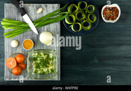 La courgette dans l'arrière-plan. Les jeunes courgettes en rondelles frites dans une casserole sur un fond sombre. La vue du sommet. Copy space Banque D'Images