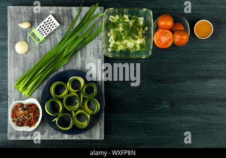 La courgette dans l'arrière-plan. Les jeunes courgettes en rondelles frites dans une casserole sur un fond sombre. La vue du sommet. Copy space Banque D'Images