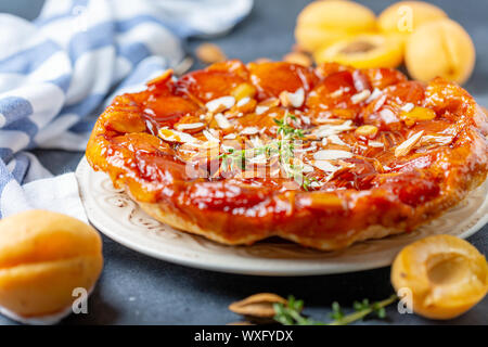 Tarte tatin aux abricots et amandes sur une assiette blanche. Banque D'Images