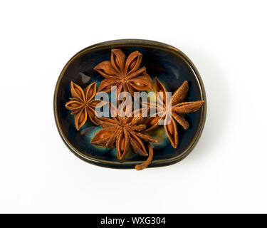 L'anis dans un bol isolé sur un fond blanc. Isoler sur l'assaisonnement. Vue de dessus. Vue rapprochée de l'anis étoile. Banque D'Images