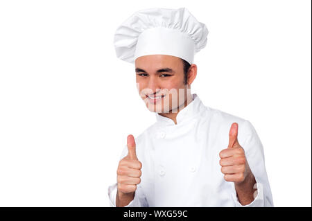 Young male chef en uniforme blanc montrant le double Thumbs up Banque D'Images