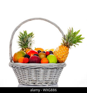 La composition avec fruits assortis dans panier en osier sur fond blanc Banque D'Images
