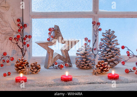 Décoration de Noël : trois étoiles, lumignons rouge feu, les baies et les cônes dans une fenêtre. La Suisse Banque D'Images