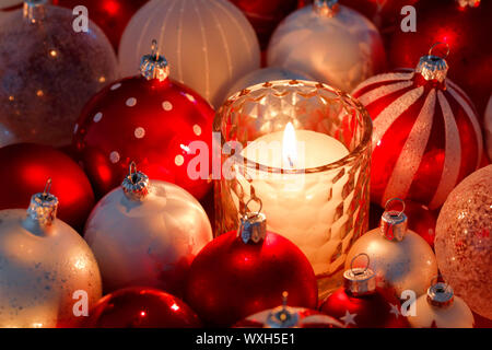 Décoration de Noël : Les bougies dans un verre entouré de boules de Noël rouge et blanc. La Suisse Banque D'Images