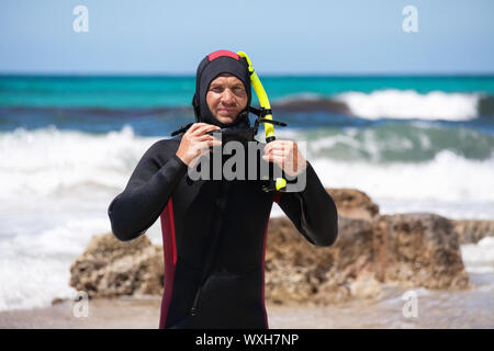 Plongeur mâle avec combinaison de plongée palmes de plongée sur la plage en été Banque D'Images