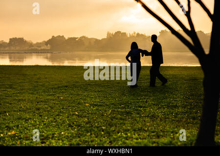 Silhouette de couple de l'exercice dans le parc, au lever du soleil. Banque D'Images