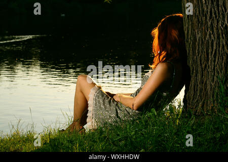 Girl sitting on tha banque de forest river Banque D'Images