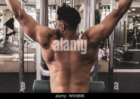 Fit man sur lat machine déroulant au club de santé. Faire de l'exercice sur machine à poids déroulant Banque D'Images