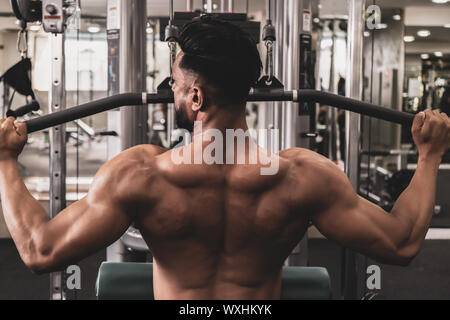 Fit man sur lat machine déroulant au club de santé. Faire de l'exercice sur machine à poids déroulant Banque D'Images