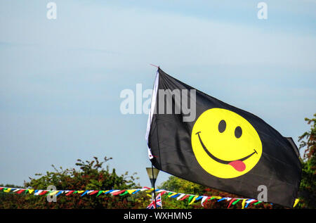 Visage souriant jaune sur l'emoji un drapeau noir Banque D'Images