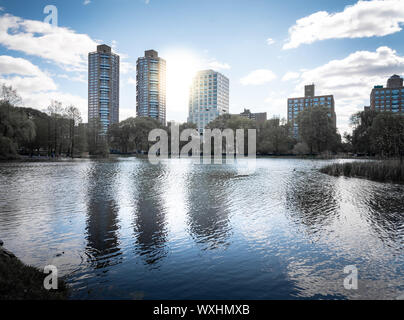 Une photo de Central Park lors d'une belle journée ensoleillée, avec ses bâtiments reflétant dans l'eau d'un lac. La ville de New York, United States Banque D'Images