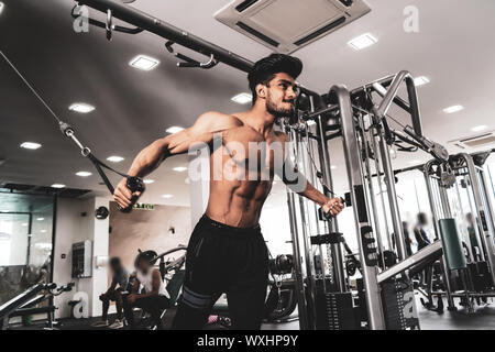 Bodybuilder travaille sur sa poitrine avec Cable Crossover dans une salle de sport. Crier pour la motivation Banque D'Images