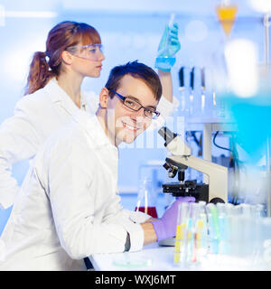Portrait d'un jeune homme microscoping chercheur dans les sciences de la vie (médecine légale, microbiologie, biochimie, génétique, oncologie...) laboratoire. Femme Banque D'Images