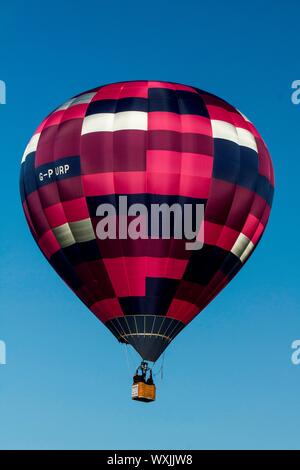 Une rose, violet, mauve et blanc de montgolfières à carreaux voler contre un ciel bleu clair.Portrait Banque D'Images