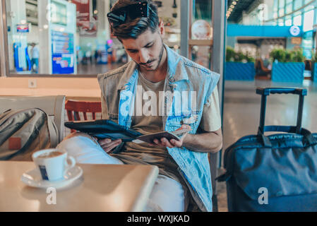 Passager utilisant digital tablet in airport departure lounge Banque D'Images