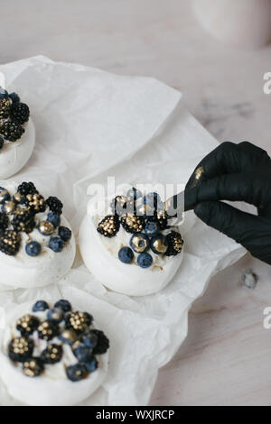 Woman decorating Pavlova desserts avec les bleuets et les mûres Banque D'Images