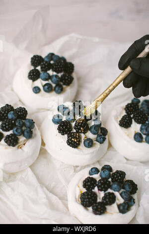 Woman decorating Pavlova desserts avec les bleuets et les mûres Banque D'Images