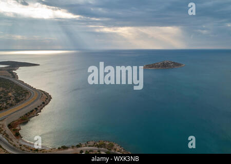 Rayons obliques briser les nuages à la surface de la mer. Île de la mer et route sinueuse dans la matinée. Vue aérienne Banque D'Images