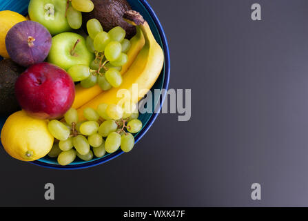 Vue de dessus de la poterie bol rempli de fruits frais biologiques sur fond sombre Banque D'Images