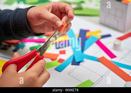 Une session d'artisanat pour enfants en face d'un enseignant de couper du papier coloré avec des ciseaux Banque D'Images