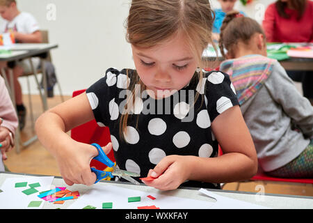 Une session d'artisanat pour enfants en face d'un enseignant de couper du papier coloré avec des ciseaux Banque D'Images