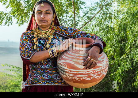 Ahir femme en tissu coloré traditionnel portant de l'eau dans une cruche d'argile, Grand Désert du Rann de Kutch, Gujarat, Inde Banque D'Images