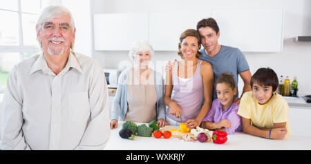 Grand-père debout par comptoir de la cuisine avec la famille derrière lui Banque D'Images