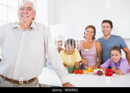 Grand-père debout à côté cuisine avec comptoir de famille derrière lui Banque D'Images