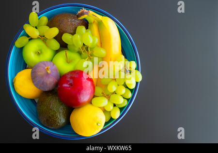 Vue de dessus de la poterie bol rempli de fruits frais biologiques sur fond sombre Banque D'Images