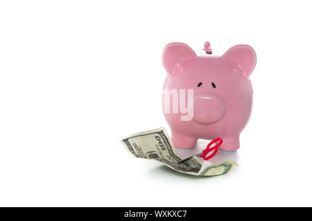 Coupe ciseaux par dollar bill in front of piggy bank on white background Banque D'Images