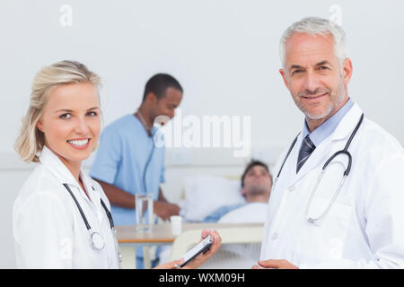 Smiling doctors standing et souriant à la caméra en face de patient Banque D'Images