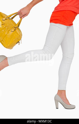 Femme en hauts talons se précipiter avec sac jaune sur fond blanc Banque D'Images