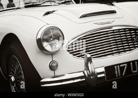 D'un quart avant droit classic vintage Austin Healey 3000 Voiture de sport présenté en noir et blanc avec un effet film granuleux. Montrant les projecteurs, radi Banque D'Images