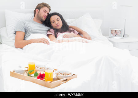 Couple dans leur lit à côté de leur petit-déjeuner Banque D'Images