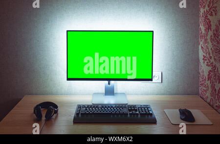 Chromakey vierge surveiller avec clavier et souris avec rétro-éclairage sur mur gris in dark room Banque D'Images