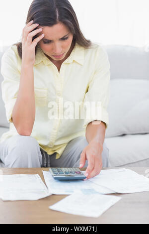 Femme faisant ses comptes a souligné sat on a couch Banque D'Images