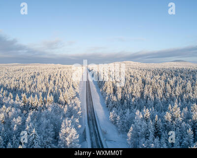 Vue aérienne d'une route au milieu de vastes forêts de la taïga à l'hiver en Finlande Banque D'Images