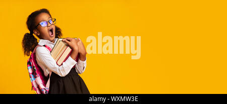 Élève d'école élémentaire Afro Girl Holding Books béant, fond jaune, Panorama Banque D'Images