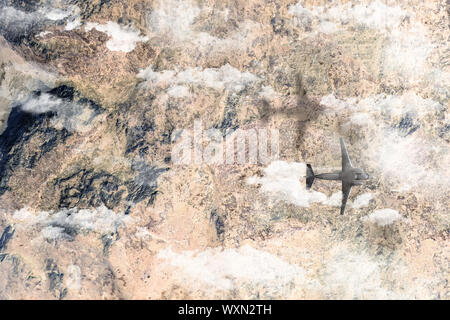 Avion vole au-dessus de montagnes dans les nuages et jette une ombre sur la terre. Haut de la télévision vue sur les roches terrestres vol de terrain Banque D'Images