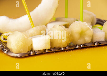 Melon sorbet aux fruits faits maison orange granité de sucettes glacées et tranches de fruits frais melon mûr sur le bac plus sur fond bleu jaune. été desse Banque D'Images