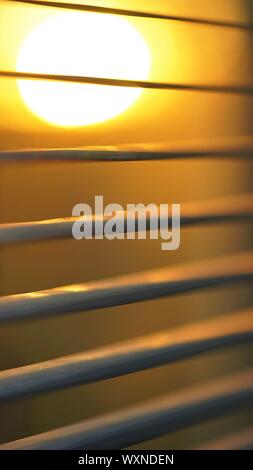 Coucher de soleil derrière stores horizontaux, macro photo. Banque D'Images