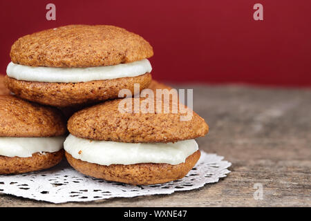 Pile de citrouille maison Whoopie Pies ou la Lune fait des tartes au fromage à la crème glaçage. Banque D'Images