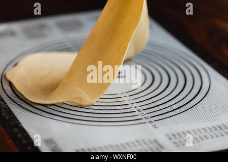 La pâte feuilletée sur un tapis de silicone pour la pâte Banque D'Images