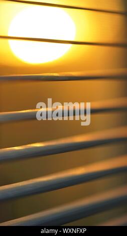 Coucher de soleil derrière stores horizontaux, macro photo. Banque D'Images