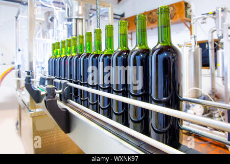 La mise en bouteille en verre de vin rouge dans la machine à la winery Banque D'Images