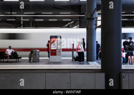 Les passagers sont debout sur une plate-forme comme un train s'éloigne, à l'intérieur de la gare principale (Hauptbahnhof), Berlin, Allemagne. Banque D'Images