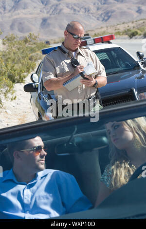 Policeman writing speeding ticket pour couple Banque D'Images