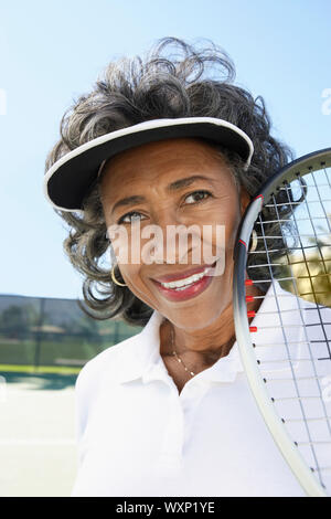 Femme souriante sur le court de tennis Banque D'Images