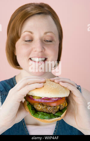 Mid-adult woman holding hamburger Banque D'Images